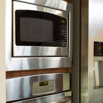 A stainless wall oven and a built-in microwave stacked in a cabinet column beside the refrigerator.